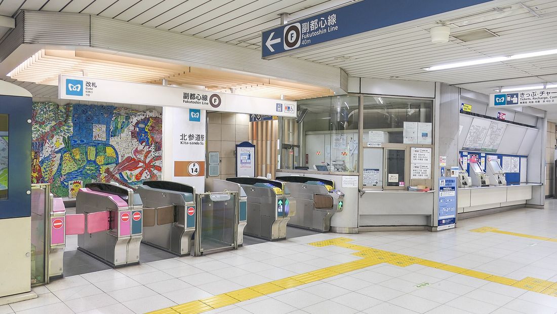 Subway ticket gates at Kita-sando with an attended window beside them, under a sign carrying the station's F 14 code.