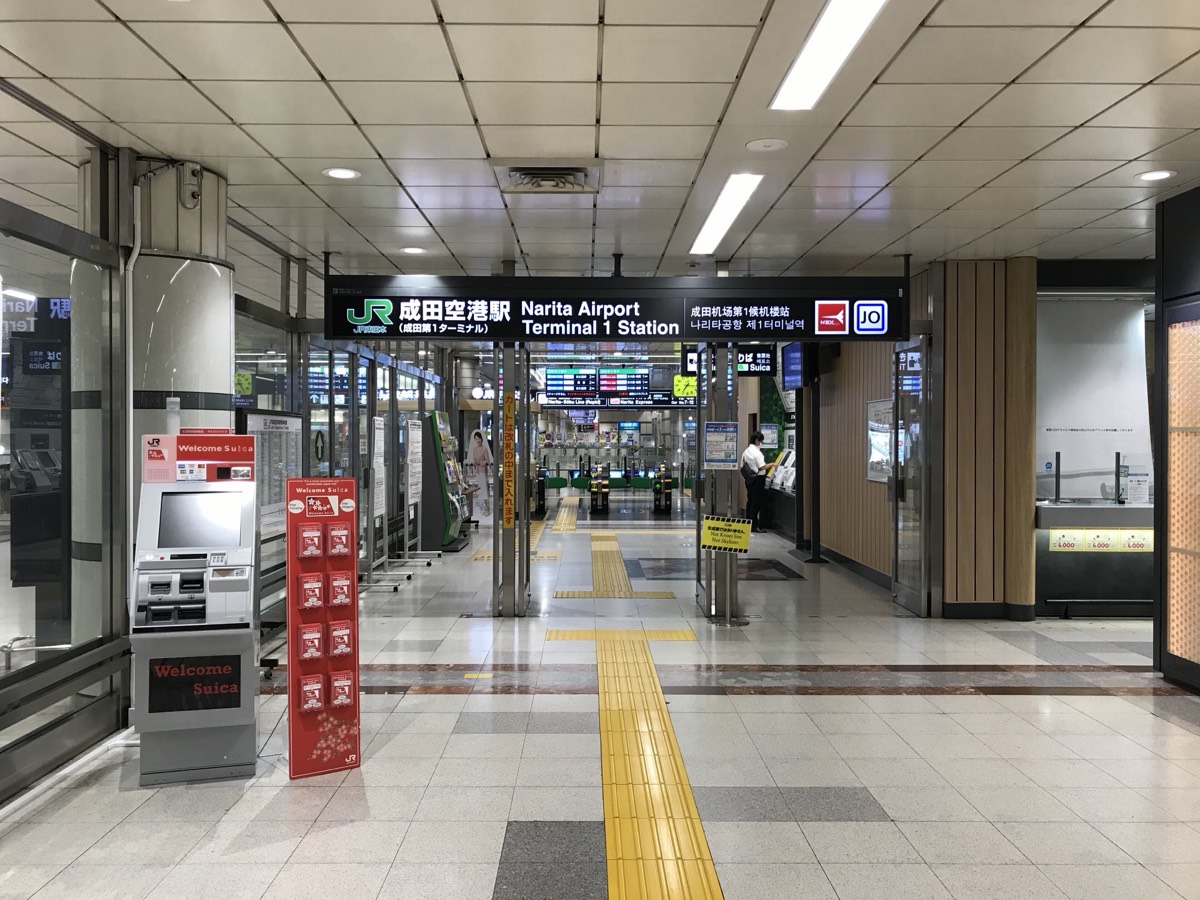 The Narita Airport Terminal 1 station sign in Japanese, English, Chinese and Korean, with the JO line symbol beside it.